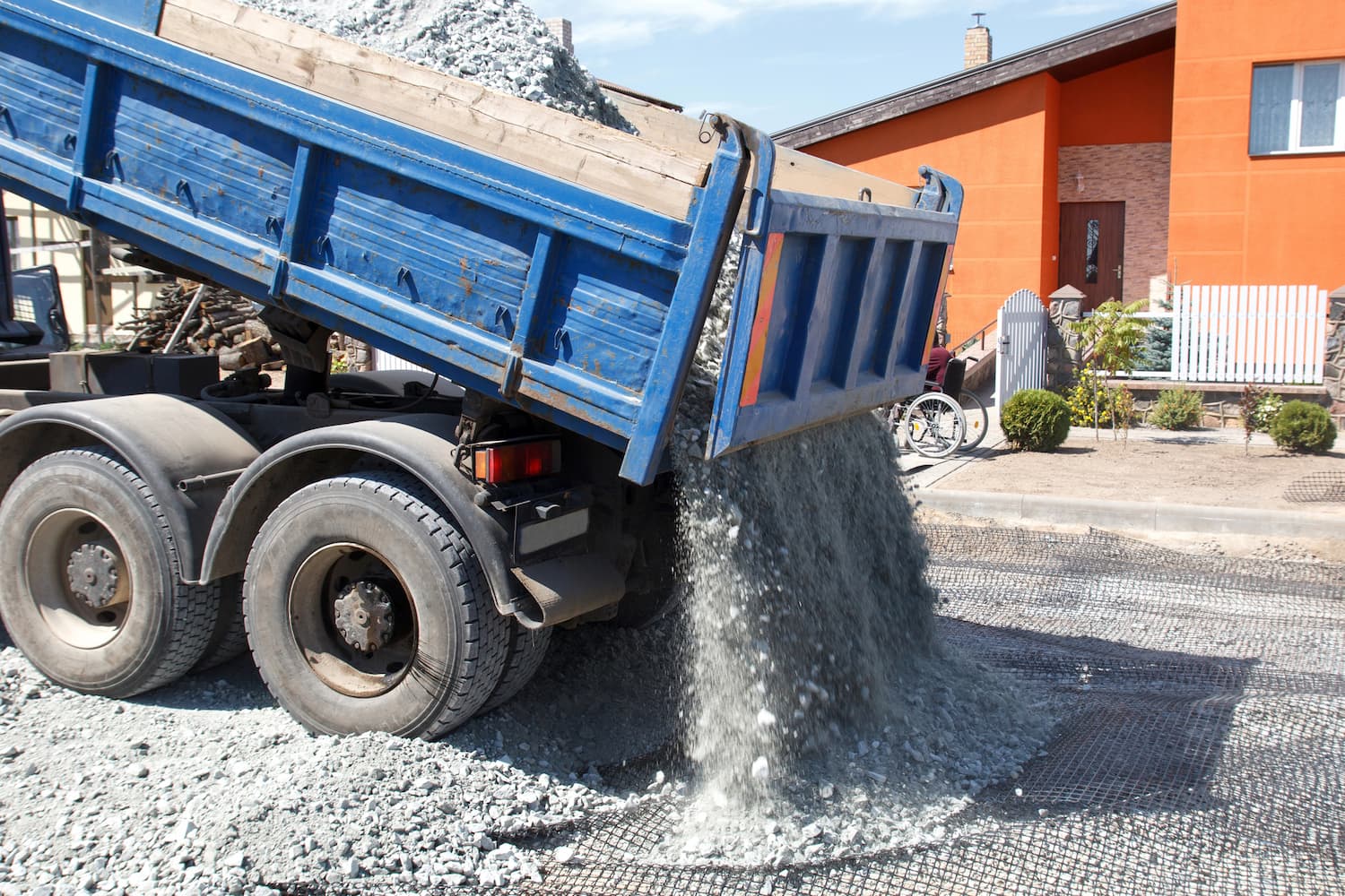dump truck dumping load of gravel on a road