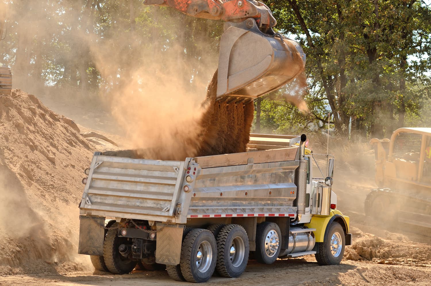 dump truck on construction site receiving load from an excavator bucket