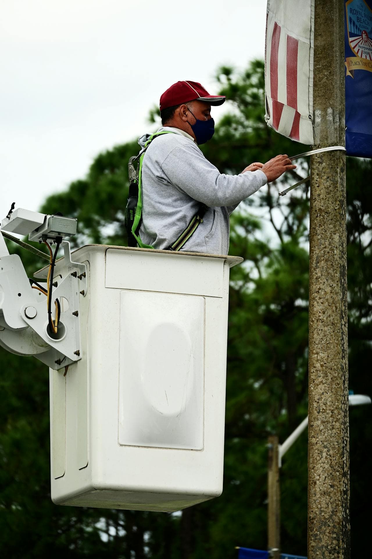 man using bucket truck to fix flag pole