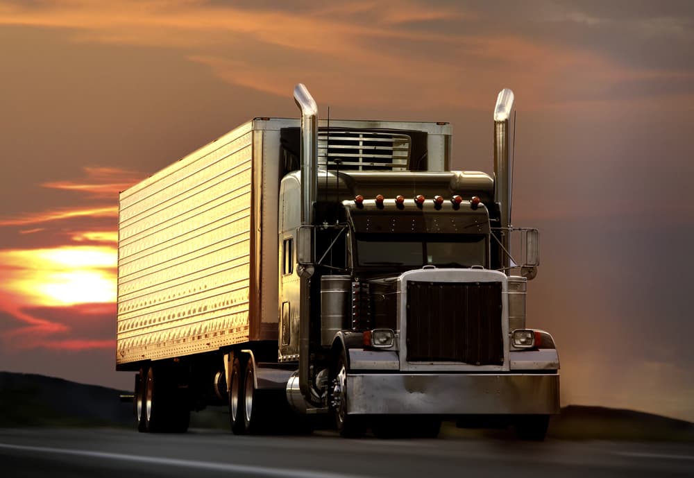 big rig semi truck on highway with sunset