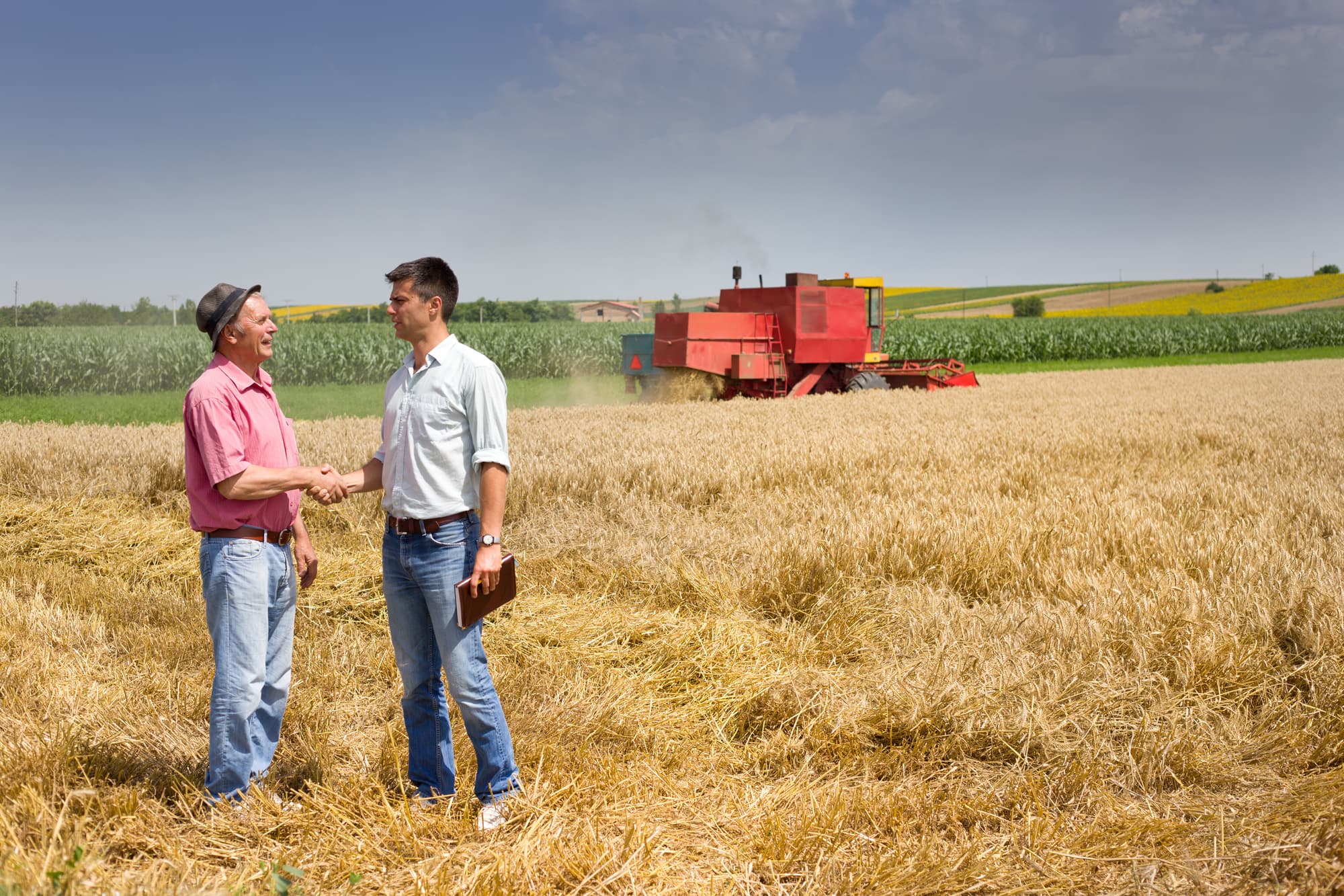 farmer shaking hands with salesman over equipment