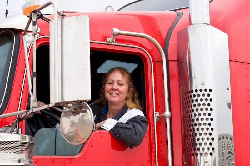 female truck driver in classic red semi truck