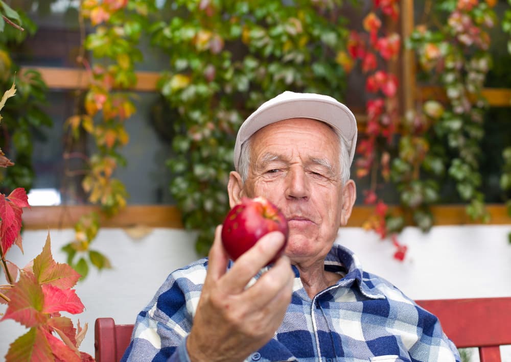 senior man looking at apple eating